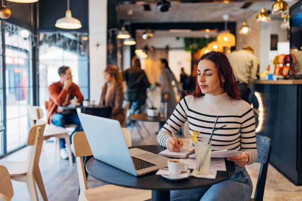 istock Female freelancer arranging paperwork while sitting at a table in a coffee shop. The concept of remote work 2191172459