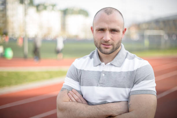 Portrait of a determined man standing outside on a track, expressing confidence and strength.