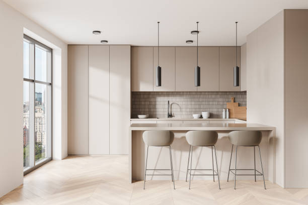 istock Beige home kitchen interior with bar counter, cooking cabinet near window 2191175099