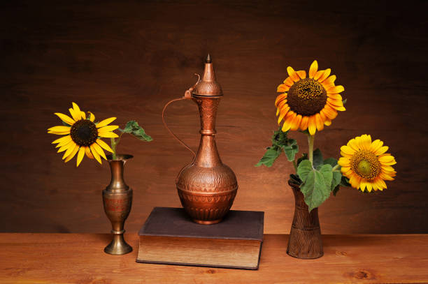 istock Still life, sunflower in a vase, copper dishes and a book 2191176436