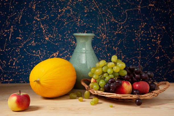 Still life, melon, ceramic vase and various fruits on a wooden table