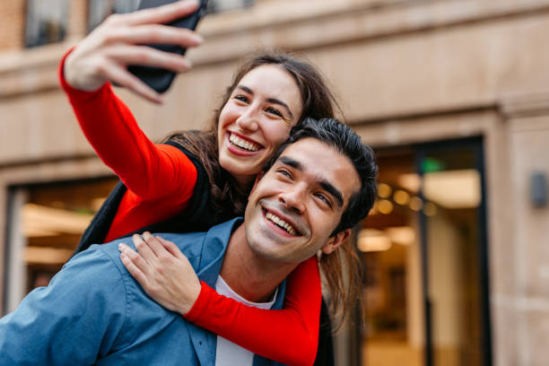 istock Girlfriend Taking Selfies Using Phone While Her Boyfriend Is Giving Her A Piggyback Ride On The Street In Shanghai In China 2191178976
