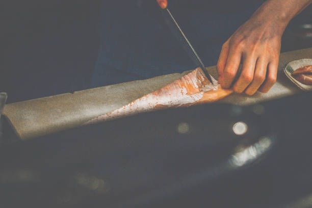 japaese chef's hands cutting up salmon belly in a restaurant