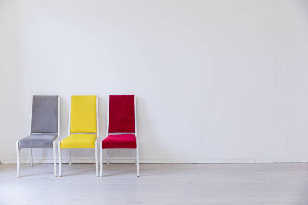 istock Three multicolored chairs in the interior of an empty white room 2191182308
