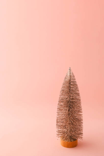 Minimalistic Christmas tree decoration covered in snow on a pastel pink background. Festive and clean composition perfect for holiday themes or modern designs