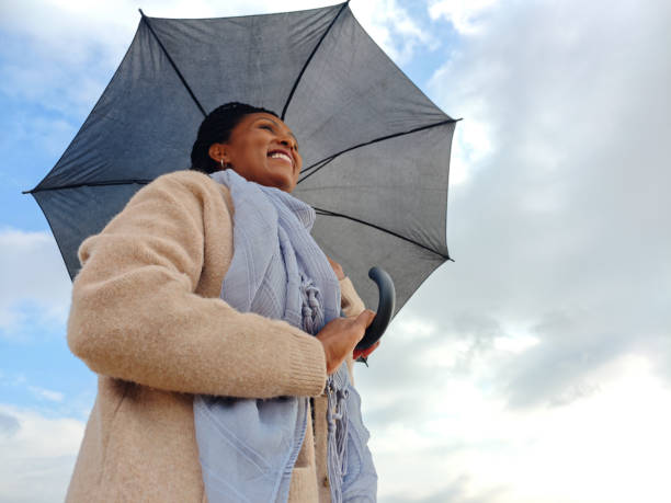 istock Confident Woman Holding an Umbrella Beneath a Cloudy Sky. 2191184419