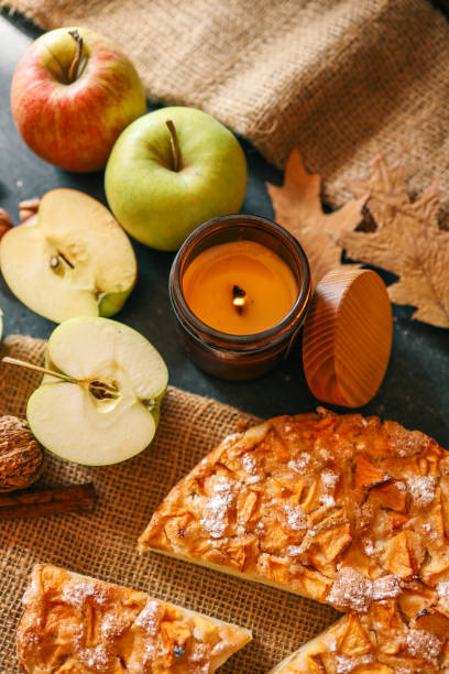 istock A cozy autumn setup featuring a freshly baked apple pie surrounded by apples, walnuts, a candle, and a warm drink 2191184609