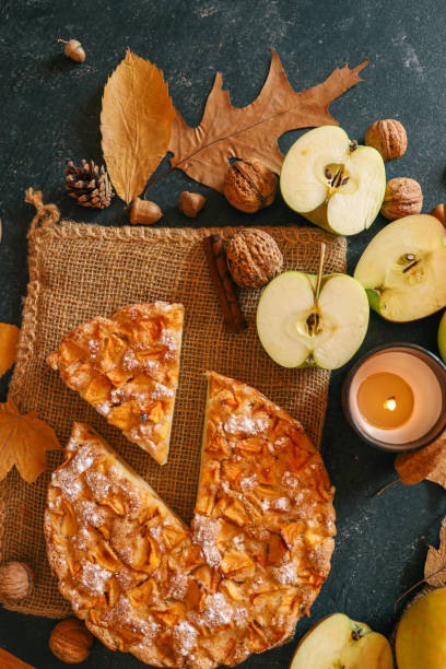 istock A cozy autumn setup featuring a freshly baked apple pie surrounded by apples, walnuts, a candle, and a warm drink 2191184656