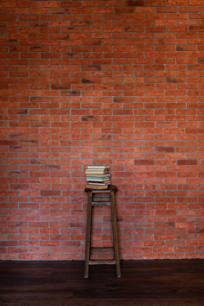 Wooden Chair and Stack of Books by Brick Wall