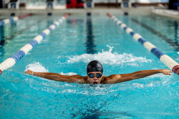 Swimmer boy swims butterfly swimming style in the pool. Closeup
