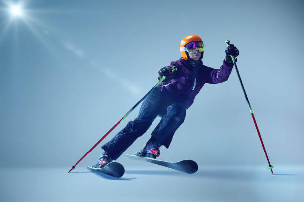 istock Winter athlete launching dynamically, orange helmet and reflective goggles glinting under studio lighting, emphasizing speed against seamless blue. 2191186904