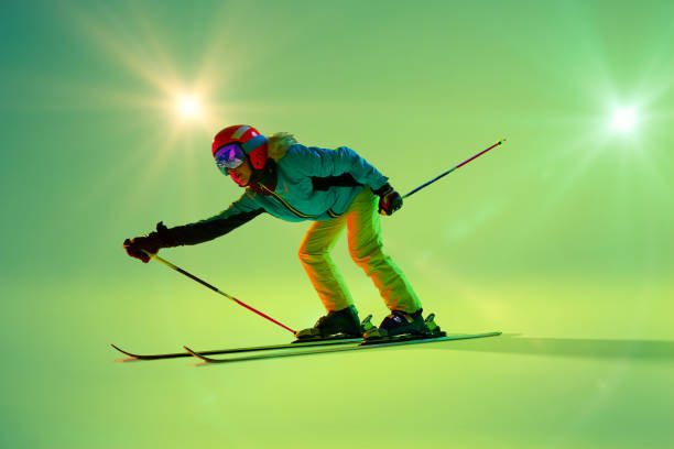 istock Crouched low, skier glides forward with skis angled slightly against bright green background enhancing action and modern aesthetic. 2191186920