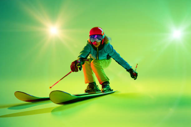 istock Female skier balances skillfully holding poles angled backward, while green background. Fresh and dynamic vibe. Movement. 2191186928
