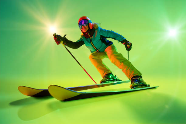 istock Side view, low angle of athletic woman, skier gliding forward against intense green studio background in neon green ambiance. 2191186939