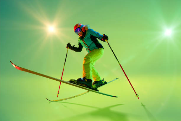 istock Freestyle skier mid-air, executing dynamic jump with bent knees and balanced posture, dressed vibrant gear against glowing studio background. 2191186946