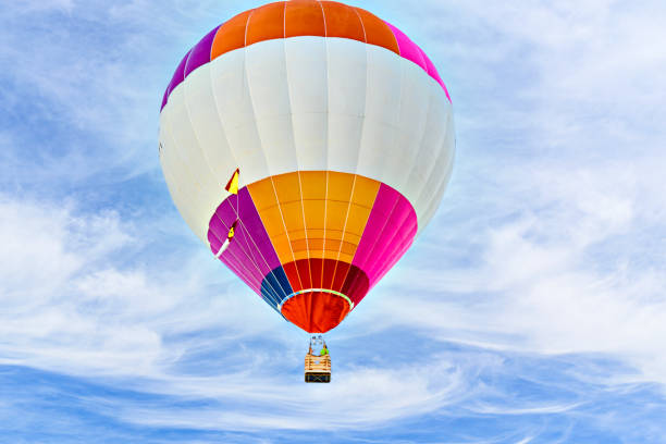 Colorful hot air balloon flying over blue sky with white clouds