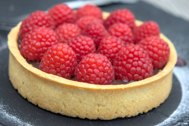 raspberry chocolate tart (beautiful fresh fruit berry dark cocoa sauce cake) red berries sweet cafe served with fork on slate slab restaurant coffee shop