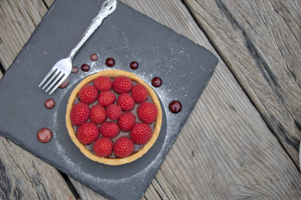 raspberry chocolate tart (beautiful fresh fruit berry dark cocoa sauce cake) red berries sweet cafe served with fork on slate slab restaurant coffee shop