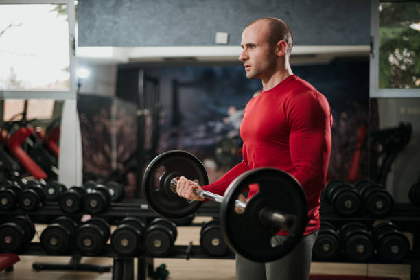 istock Man Lifting Dumbbells in Modern Gym Environment for Strength Training 2191195473