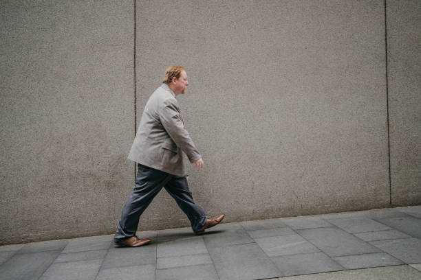 istock Man strides against textured wall in formal grey suit. 2191195548