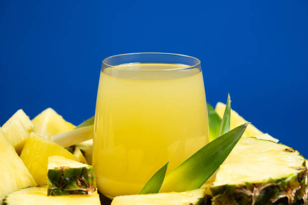 Pineapple juice in a glass among fresh pineapple fruit close-up