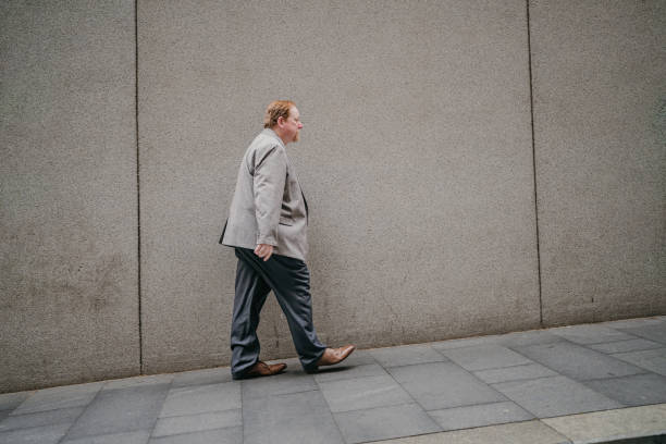 Person in grey on city sidewalk against flat facade.