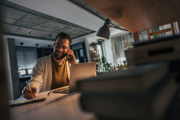 istock The man is multitasking, writing in a notebook with a pen while talking on his smartphone. 2191196730