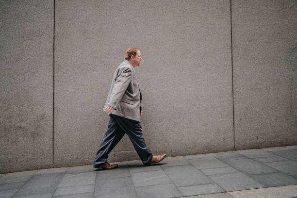 istock Urban professional walks in grey suit beside wall. 2191197701