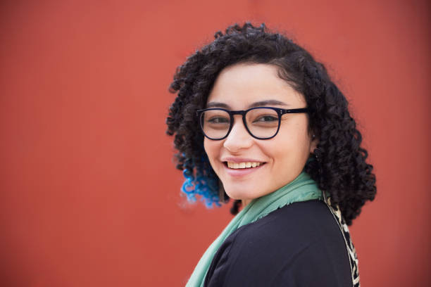 istock The young woman, poses for a portrait against a simple, plain-colored background. 2191199149