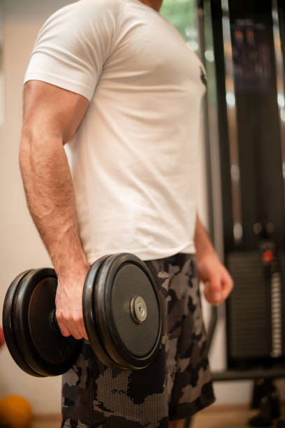 istock Side Profile of Man Working Out With Dumbbells in a Gym Setting 2191199983
