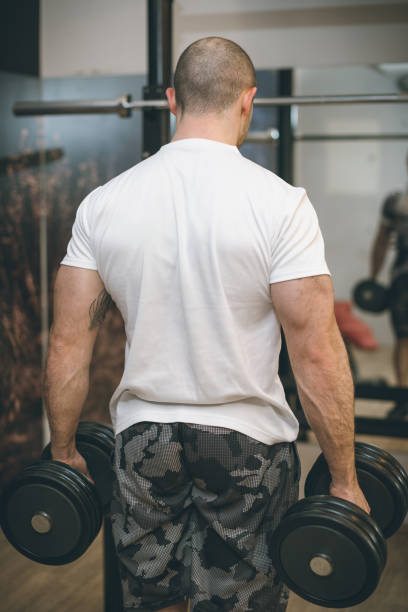 istock Back View of a Man Exercising with Dumbbells in a Gym Setting 2191199995
