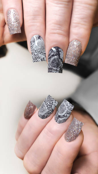 istock Acrylic nail extensions with a snake design and glitter gel polish. Manicure 2191201817