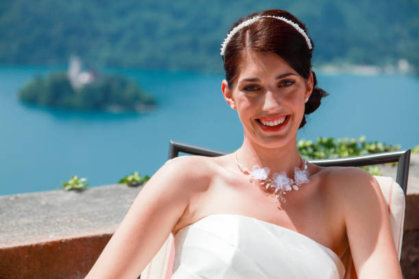 Smiling woman in white dress sitting on a balcony over a lake. Lake Bled - Slovenia.