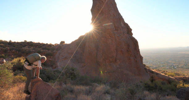 istock Mature backpacker climb onto rock below spire 2191202898