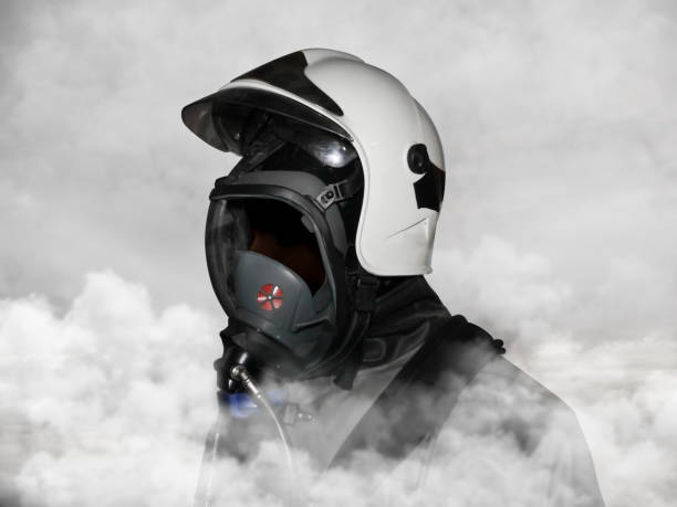 istock Fireman wearing helmet in thick depths of smoke front side angle view 2191203059