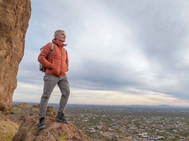 Aerial view of hiker pausing on rock below spire and baove valley, Apache Junction, AZ