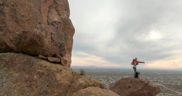 Aerial view of hiker pausing on rock below spire