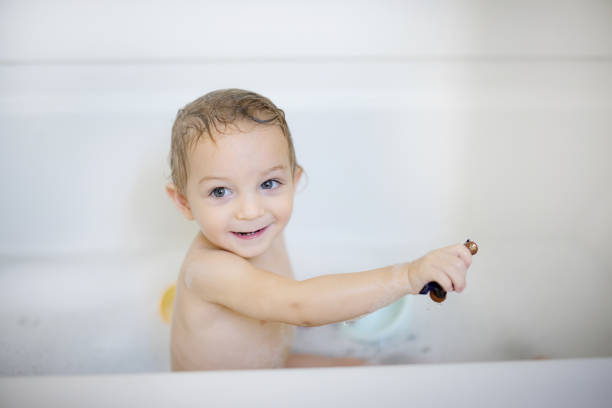 A cheerful young child having fun during bath time, surrounded by toys and bubbles, creating a joyful and playful moment. Capturing the essence of childhood and happiness within a domestic environment.