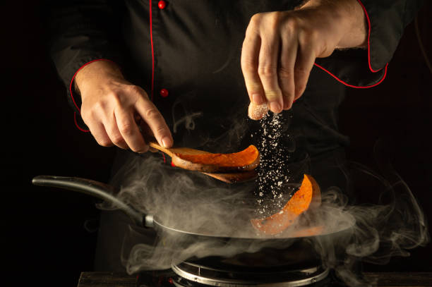 istock In a dimly lit kitchen, a chef expertly seasons pumpkin slices with salt, creating a fragrant mixture. Wisps of steam rise, adding a touch of culinary art to the moment 2191205422