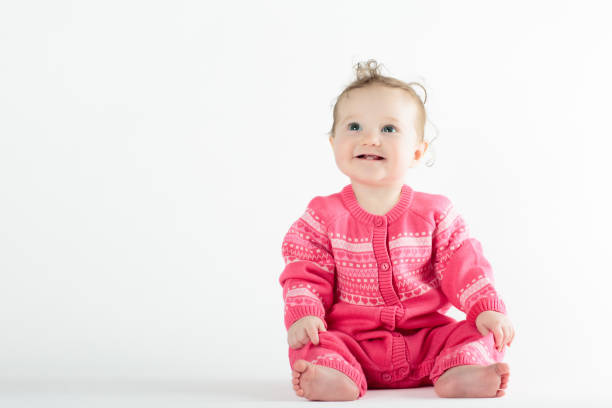 Adorable baby in white sunny bedroom. Newborn child relaxing in bed. Nursery for young children. Textile and bedding for kids. Family morning at home. New born kid during tummy time with toy bear.