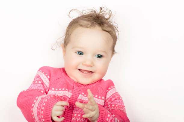 portrait of a laughing baby in summer on the green grass in a red bodysuit enjoying the fresh air, close-up
