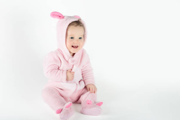 Adorable baby in white sunny bedroom. Newborn child relaxing in bed. Nursery for young children. Textile and bedding for kids. Family morning at home. New born kid during tummy time with toy bear.