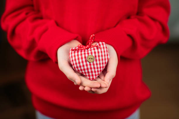 Child holding toy heart. Valentine’s day greeting. Christmas ornament in heart form.