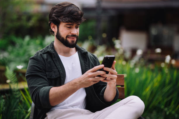 istock Side view of young man checking messages at the campus courtyard 2191209964