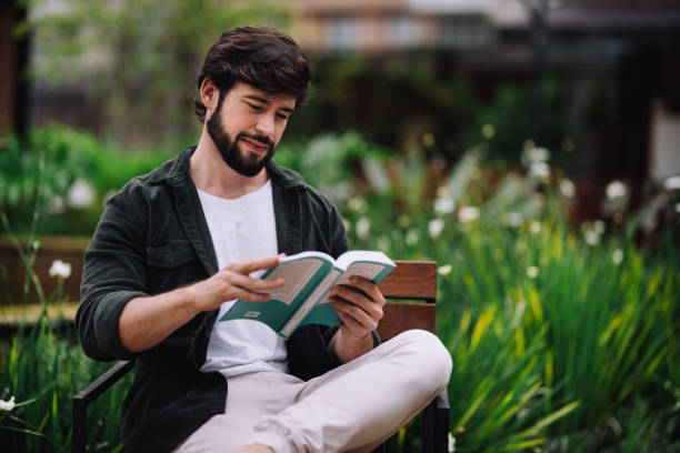 Young intellectual man reading a book at a public park
