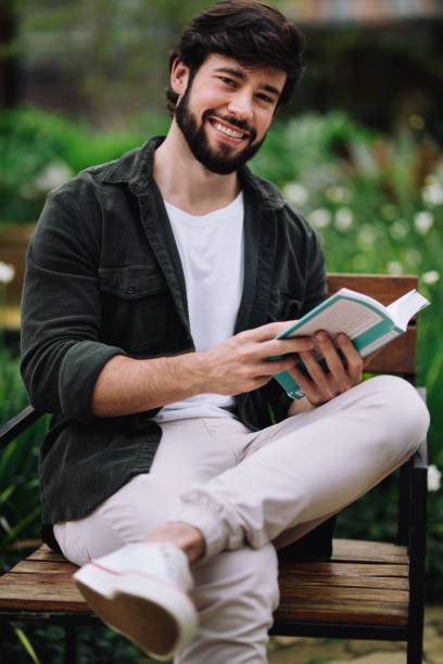 istock Front view of young man reading a book at the university campus 2191210712
