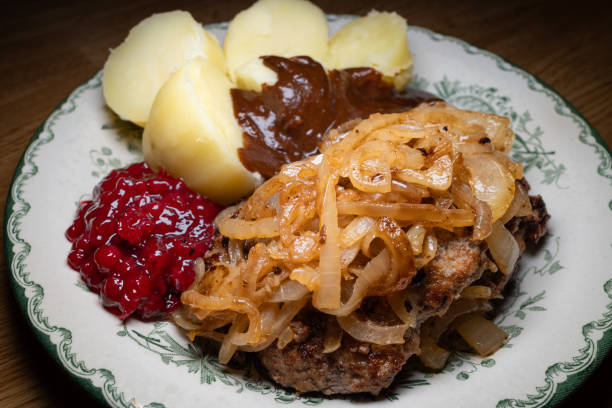 Traditional Swedish minced beef patties with fried onion, potatoes, creamy gravy and lingonberry stock photo