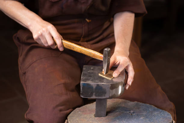 istock craftswoman - blacksmith hammering metal 2191220413
