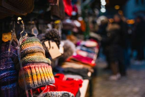 Vibrant winter hats and knitted accessories on display at a Christmas market stall in Berlin. The colorful collection of beanies, scarves, and gloves creates a cozy and festive atmosphere, perfect for holiday shoppers looking for warm gifts or seasonal wear