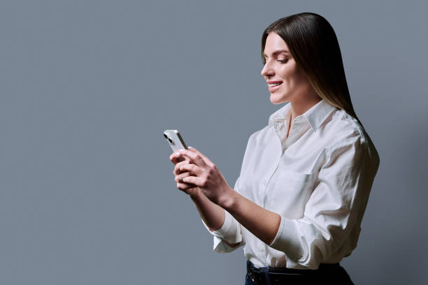 istock Profile view, young beautiful woman using mobile phone on grey background 2191230300